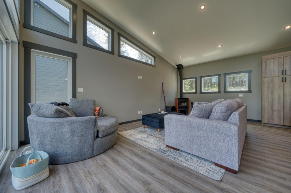 Cette photo montre une salle de séjour moderne ouverte avec un mur gris, un sol en vinyl, un poêle à bois, un sol beige et un plafond voûté.