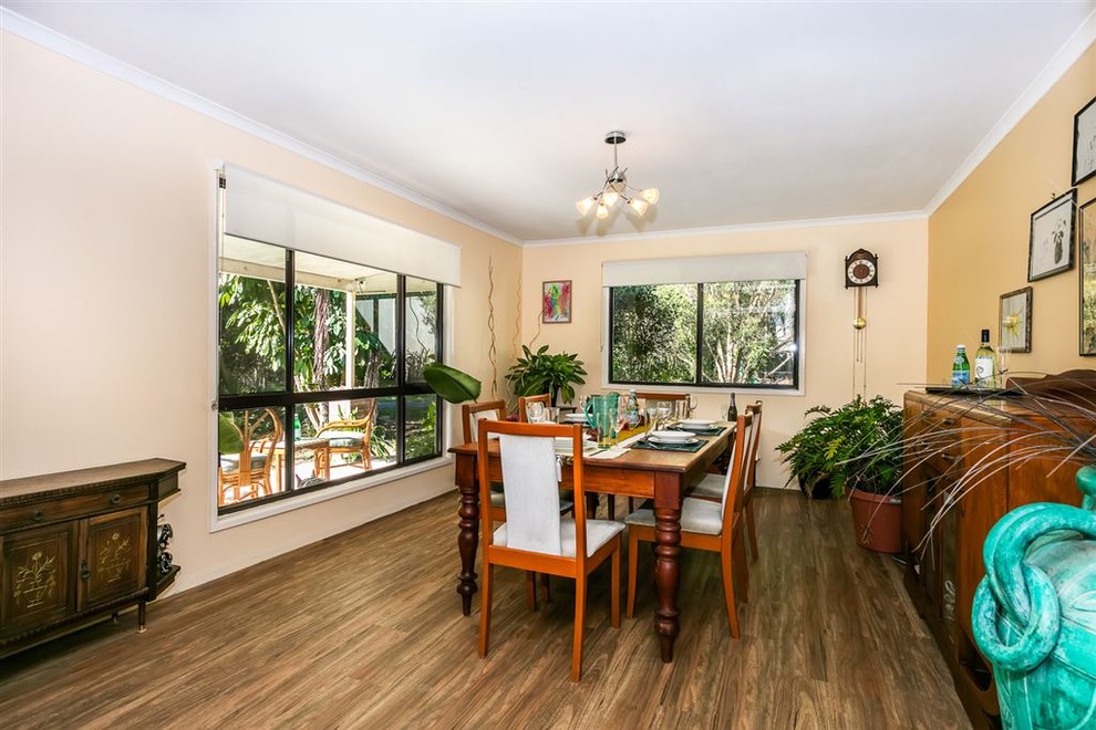 This is an example of a large country separate dining room in Brisbane with yellow walls, laminate floors and brown floor.