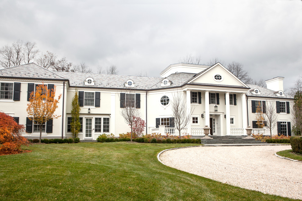 This is an example of an expansive traditional two-storey stucco green exterior in New York.
