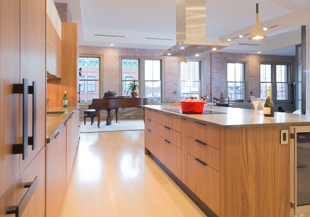 Photo of a contemporary kitchen in New York with an undermount sink, flat-panel cabinets, light wood cabinets, mosaic tile splashback, stainless steel appliances, light hardwood floors and with island.