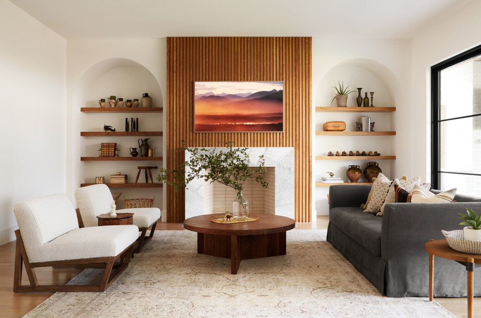 Diseño de salón actual con paredes blancas, suelo de madera en tonos medios, todas las chimeneas, televisor colgado en la pared y suelo marrón