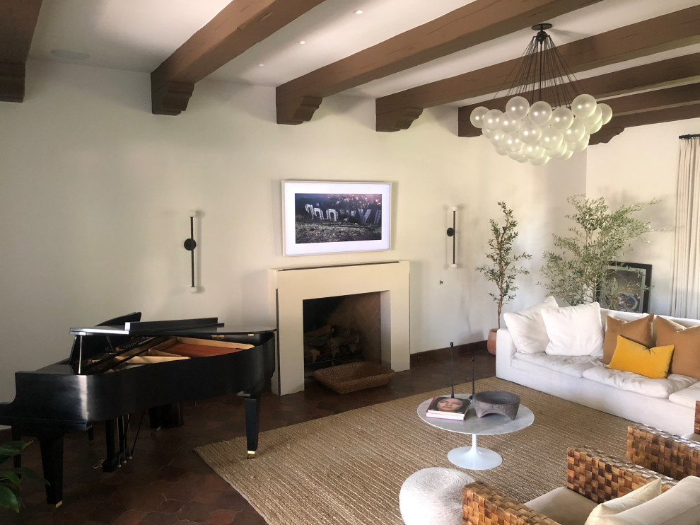 Mid-sized traditional formal open concept living room in Phoenix with white walls, terra-cotta floors, a standard fireplace, a plaster fireplace surround, a wall-mounted tv, red floor and exposed beam.
