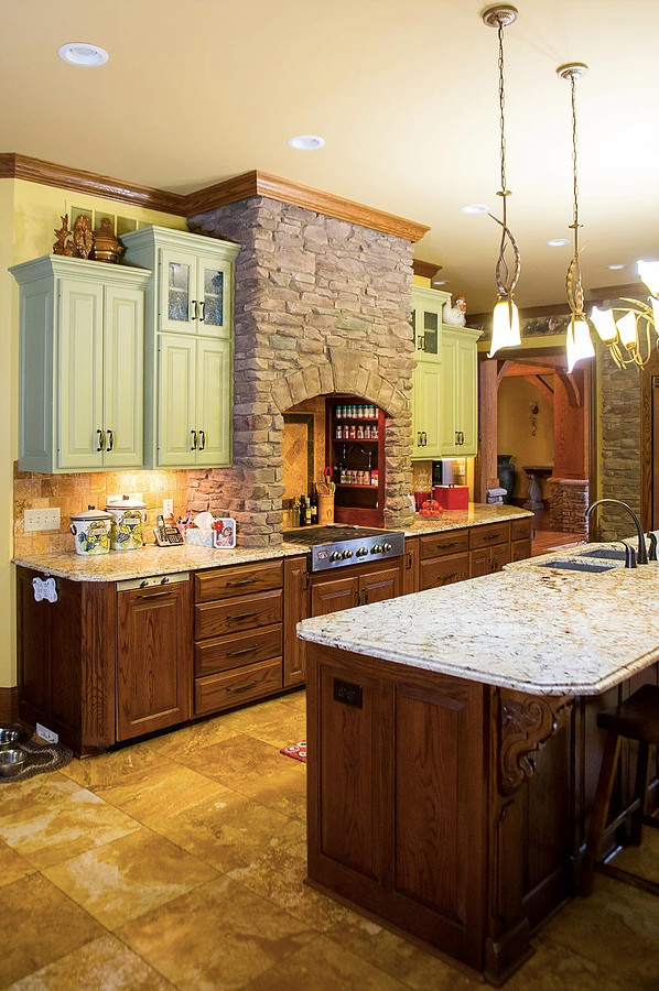 Large mountain style u-shaped porcelain tile and beige floor eat-in kitchen photo with an undermount sink, raised-panel cabinets, green cabinets, granite countertops, beige backsplash, porcelain backsplash, stainless steel appliances, an island and multicolored countertops