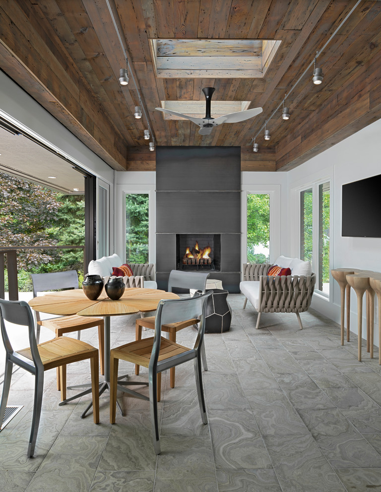 Photo of an expansive modern sunroom in Detroit with travertine floors, a standard fireplace, a metal fireplace surround, a skylight and grey floor.