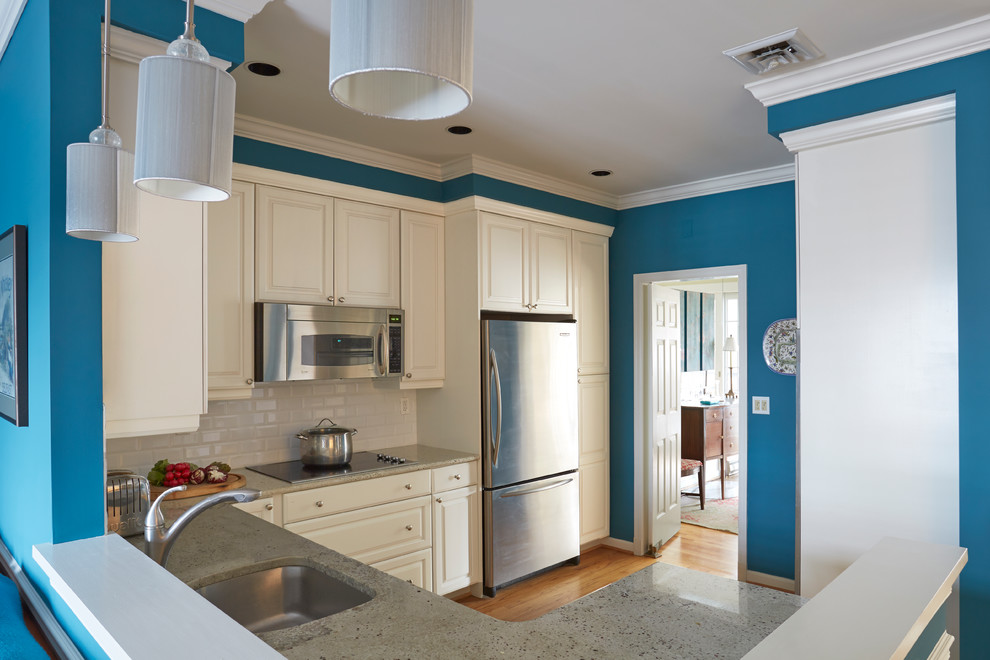Example of an u-shaped medium tone wood floor open concept kitchen design in Baltimore with an undermount sink, white cabinets, marble countertops, white backsplash, subway tile backsplash and stainless steel appliances