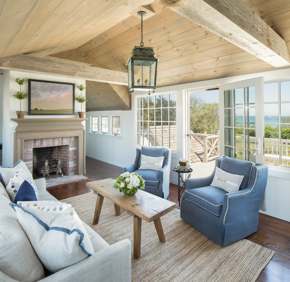 This is an example of a mid-sized beach style formal enclosed living room in Boston with white walls, dark hardwood floors, a standard fireplace, a brick fireplace surround, brown floor and no tv.