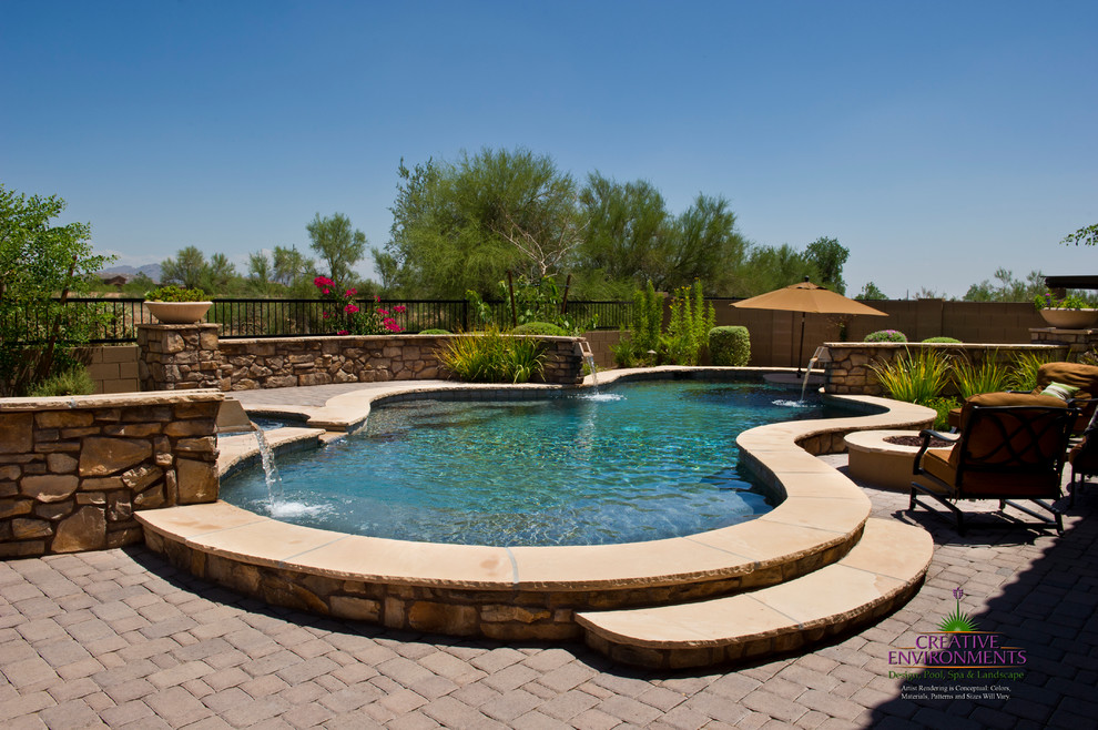 Hot tub - large backyard stamped concrete and custom-shaped hot tub idea in Phoenix