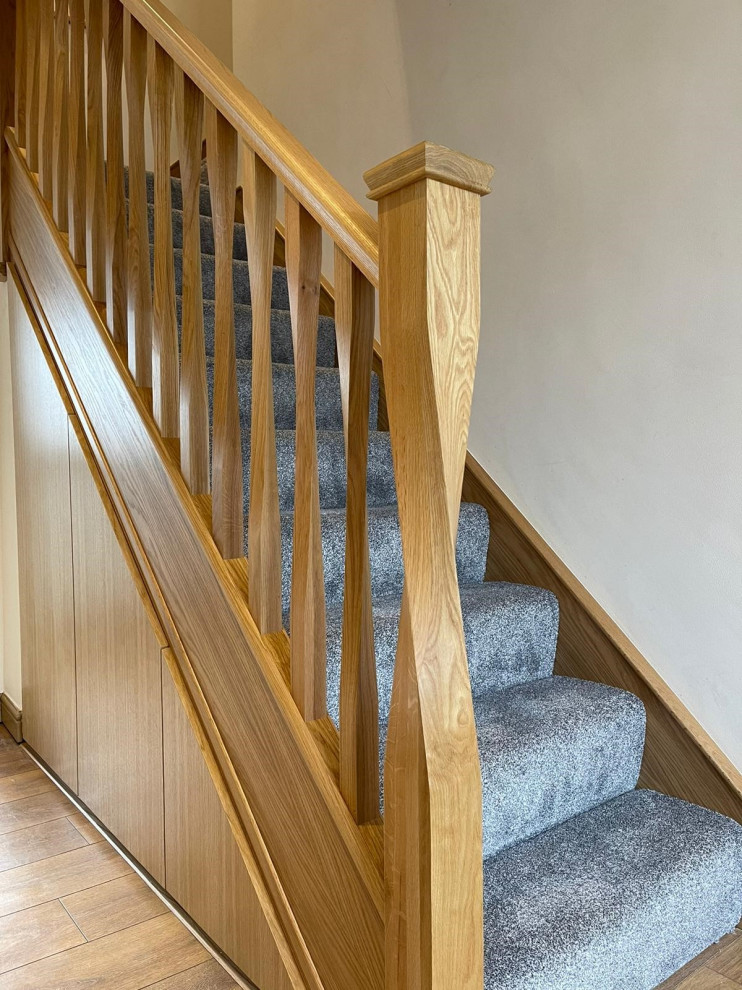 Cette image montre un escalier design en L de taille moyenne avec des marches en moquette, des contremarches en moquette et un garde-corps en bois.