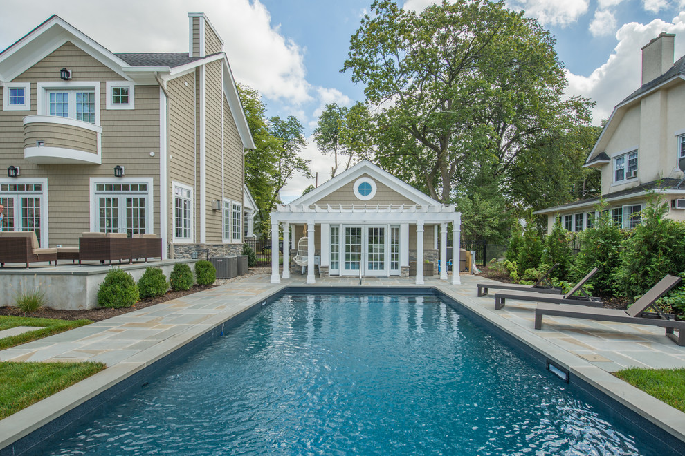 Transitional backyard rectangular lap pool in New York with a pool house.