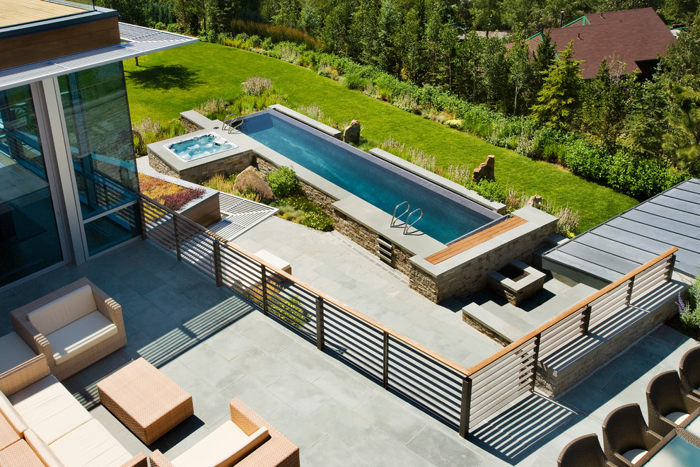 This is an example of a large contemporary backyard rectangular lap pool in Denver with a hot tub.