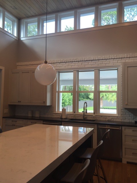 Inspiration for a large transitional l-shaped light wood floor open concept kitchen remodel in Jacksonville with an integrated sink, shaker cabinets, white cabinets, granite countertops, gray backsplash, stone tile backsplash, stainless steel appliances and an island