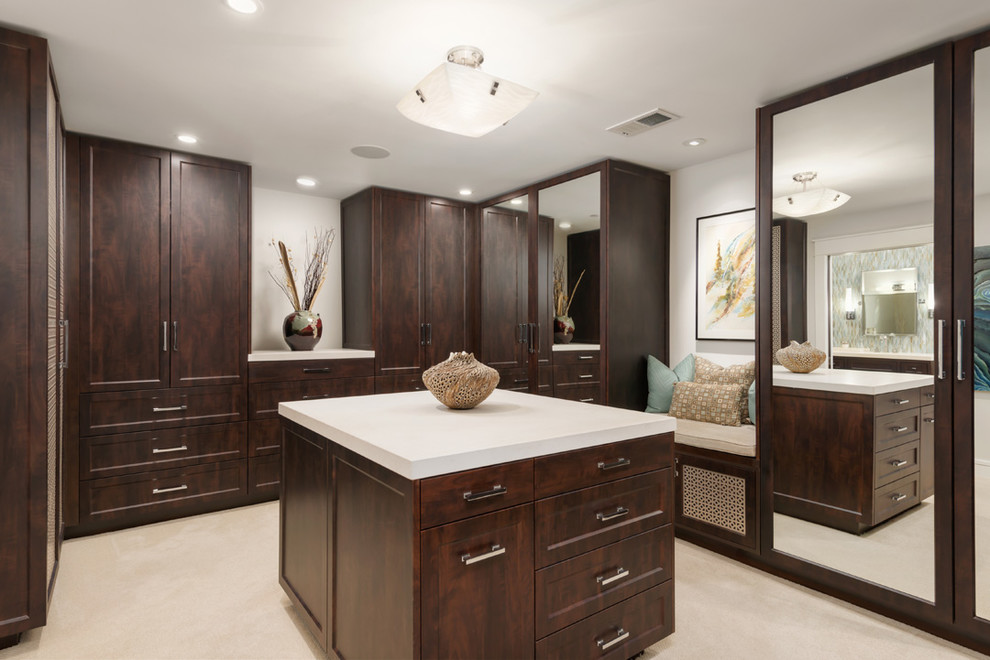 Photo of a large transitional gender-neutral dressing room in San Francisco with recessed-panel cabinets, dark wood cabinets, carpet and beige floor.