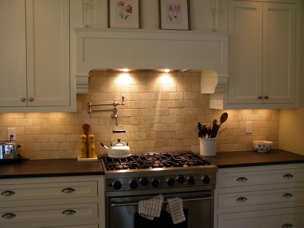 Exemple d'une cuisine chic de taille moyenne avec un placard à porte shaker, des portes de placard blanches, un plan de travail en surface solide, une crédence beige et une crédence en carrelage de pierre.