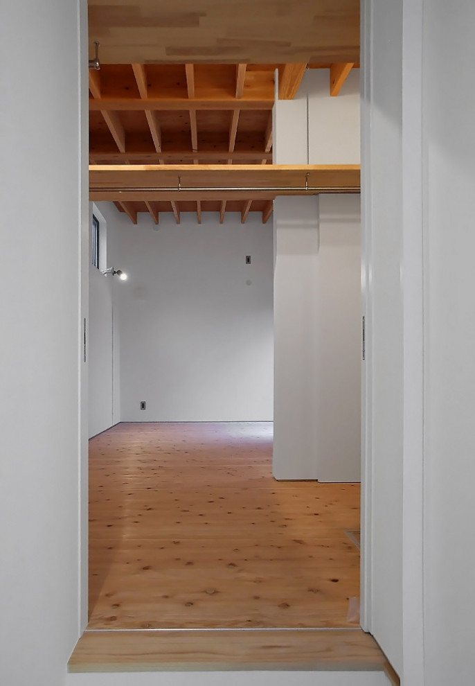 Imagen de armario vestidor unisex minimalista con armarios abiertos, suelo de madera clara y vigas vistas