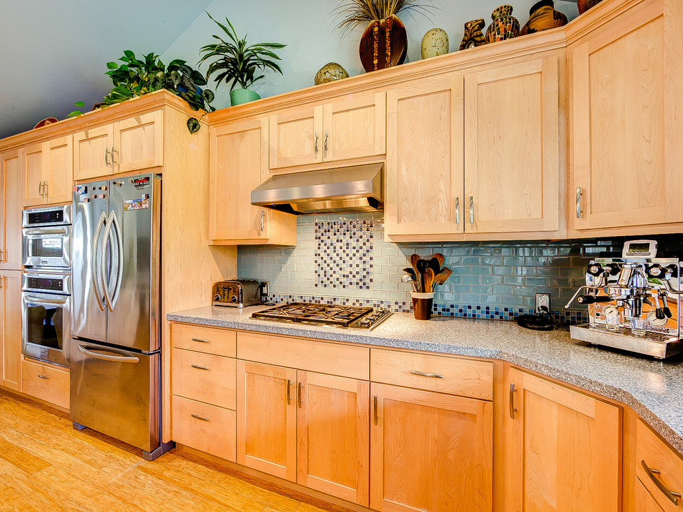 This is an example of a mid-sized beach style l-shaped eat-in kitchen in San Francisco with shaker cabinets, no island, a single-bowl sink, light wood cabinets, granite benchtops, multi-coloured splashback, mosaic tile splashback, stainless steel appliances and light hardwood floors.