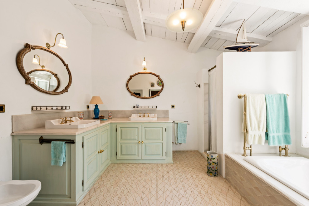 Design ideas for a mediterranean bathroom in Malaga with raised-panel cabinets, green cabinets, a drop-in tub, an alcove shower, white walls, a drop-in sink, beige floor, a shower curtain, beige benchtops, a double vanity, a built-in vanity and vaulted.