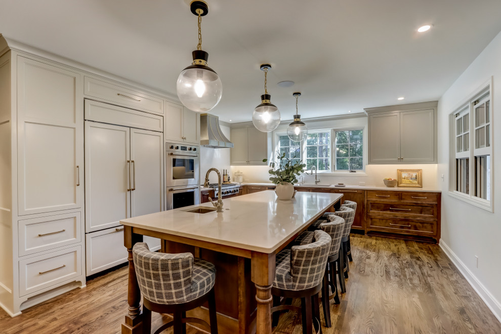 Enclosed kitchen - mid-sized transitional l-shaped medium tone wood floor and brown floor enclosed kitchen idea in Milwaukee with an undermount sink, recessed-panel cabinets, medium tone wood cabinets, quartz countertops, white backsplash, ceramic backsplash, stainless steel appliances, an island and white countertops