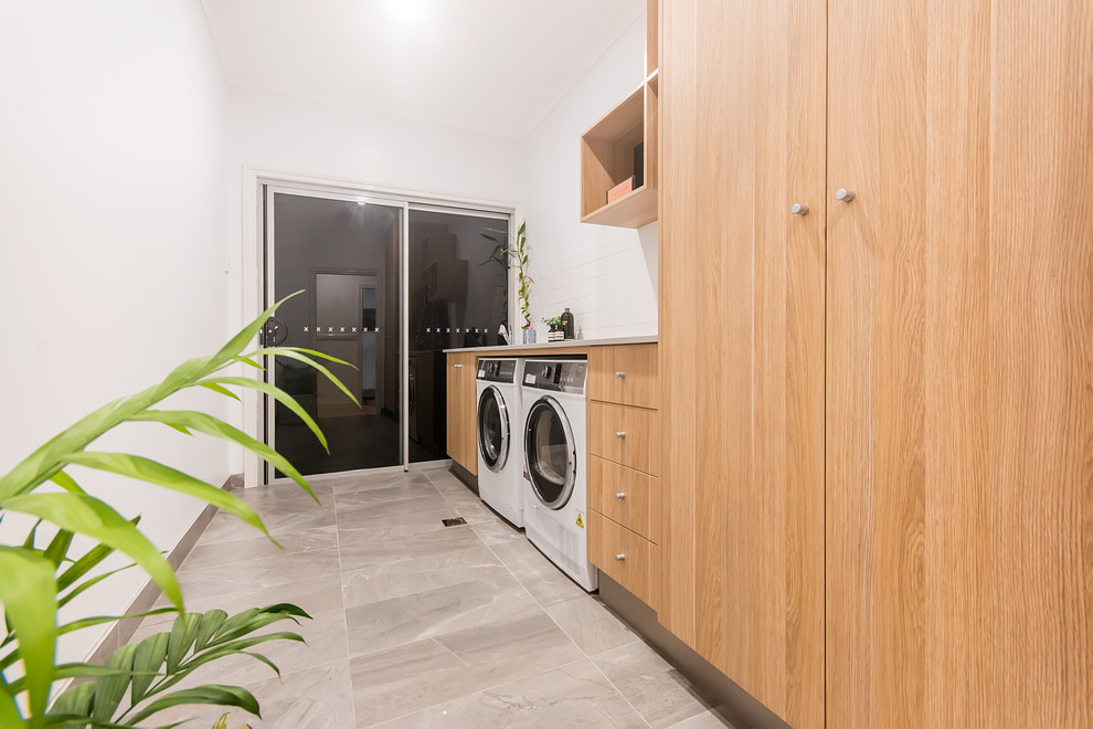 Design ideas for a mid-sized industrial single-wall dedicated laundry room in Other with a drop-in sink, flat-panel cabinets, light wood cabinets, granite benchtops, white splashback, subway tile splashback, white walls, ceramic floors, a side-by-side washer and dryer, grey floor and grey benchtop.