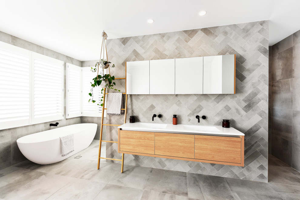 Photo of a contemporary bathroom in Other with a freestanding tub, gray tile, a double vanity, a floating vanity, flat-panel cabinets, medium wood cabinets, a curbless shower, an integrated sink, grey floor, an open shower and white benchtops.