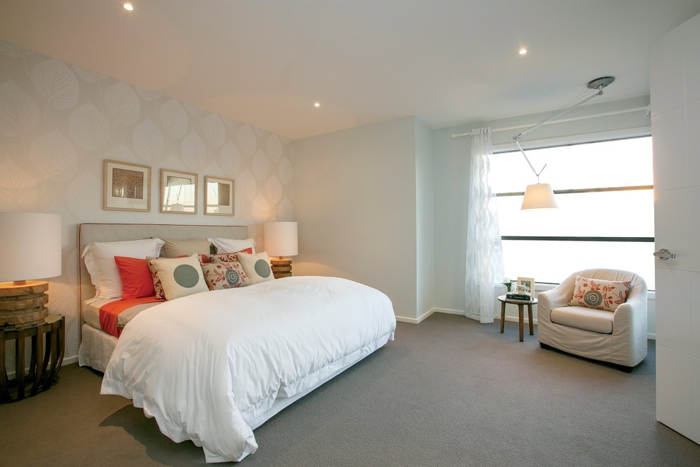 This is an example of a large beach style master bedroom in Melbourne with white walls, carpet, no fireplace and brown floor.