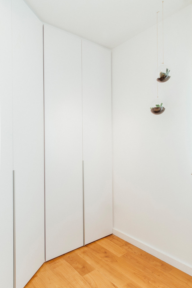 Design ideas for a mid-sized scandinavian women's built-in wardrobe in Other with flat-panel cabinets, white cabinets, medium hardwood floors and brown floor.