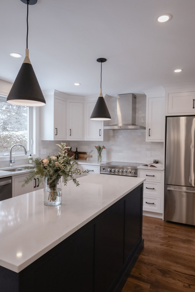 Small transitional u-shaped medium tone wood floor and brown floor eat-in kitchen photo in Ottawa with an undermount sink, shaker cabinets, white cabinets, quartz countertops, white backsplash, subway tile backsplash, stainless steel appliances, an island and white countertops