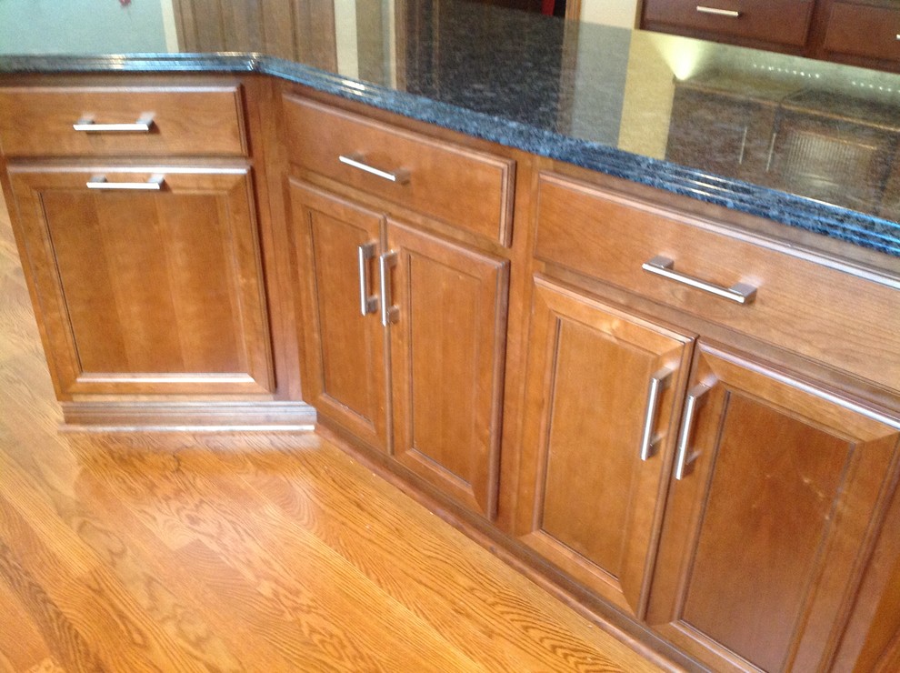 Eat-in kitchen - mid-sized transitional l-shaped medium tone wood floor eat-in kitchen idea with an undermount sink, recessed-panel cabinets, medium tone wood cabinets, granite countertops, gray backsplash, stone tile backsplash, stainless steel appliances, gray walls and an island