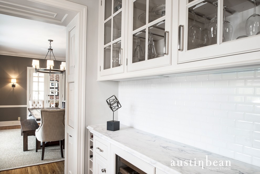 Inspiration for a transitional medium tone wood floor kitchen remodel with glass-front cabinets, white cabinets, marble countertops, white backsplash, subway tile backsplash and gray walls