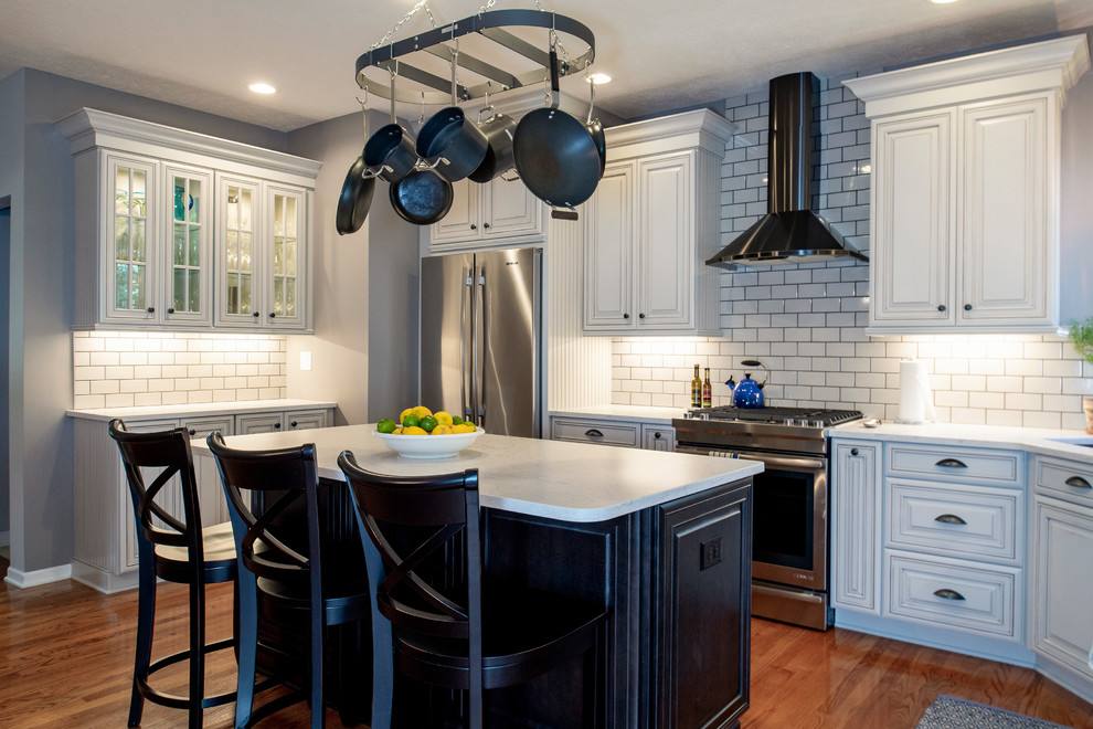 Example of a mid-sized transitional l-shaped medium tone wood floor and red floor eat-in kitchen design with an undermount sink, raised-panel cabinets, gray cabinets, quartz countertops, gray backsplash, subway tile backsplash, stainless steel appliances, an island and white countertops