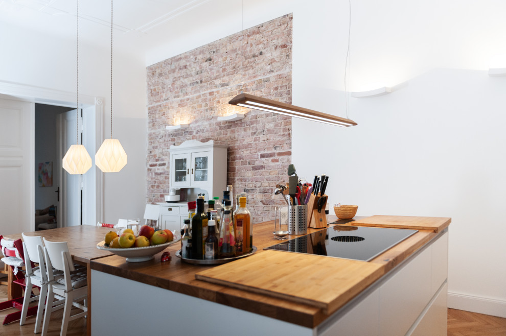 Photo of a mid-sized contemporary open plan dining in Berlin with white walls, medium hardwood floors, brown floor and brick walls.