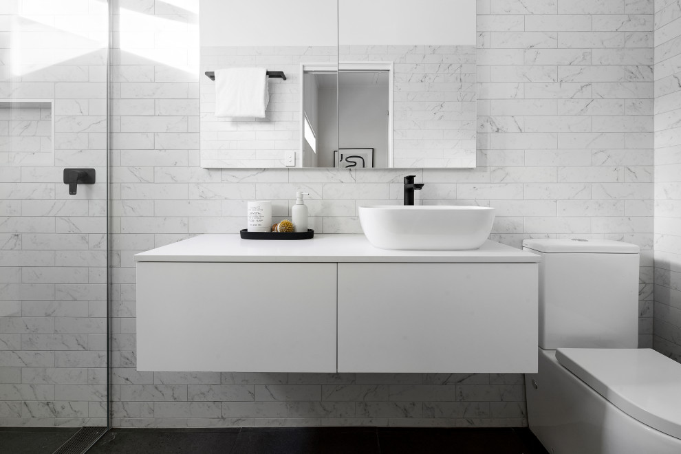 Mid-sized modern master bathroom in Melbourne with flat-panel cabinets, white cabinets, a freestanding tub, a corner shower, a one-piece toilet, gray tile, ceramic tile, white walls, ceramic floors, a console sink, engineered quartz benchtops, black floor, a hinged shower door, white benchtops, a single vanity and a floating vanity.