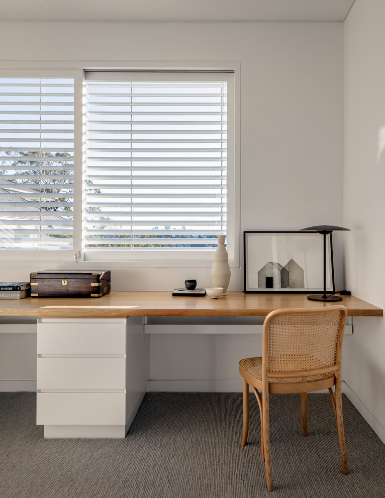 Inredning av ett modernt arbetsrum, med vita väggar, heltäckningsmatta och ett inbyggt skrivbord