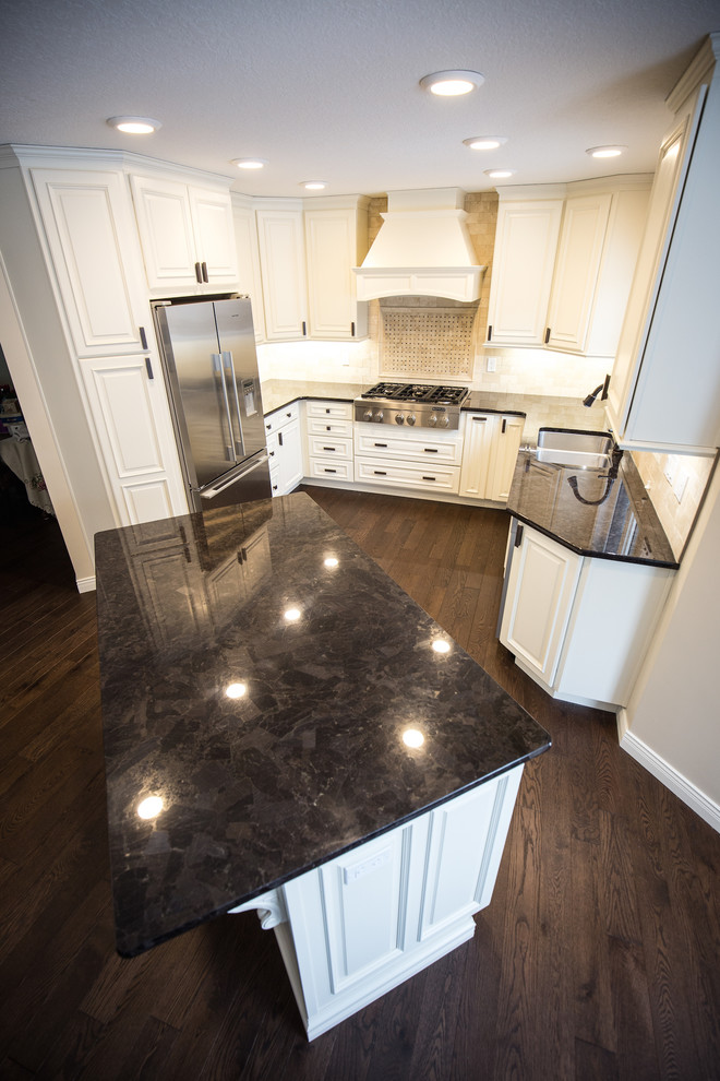 Eat-in kitchen - mid-sized traditional u-shaped dark wood floor eat-in kitchen idea in Edmonton with a drop-in sink, white cabinets, granite countertops, beige backsplash, stone tile backsplash, stainless steel appliances and an island