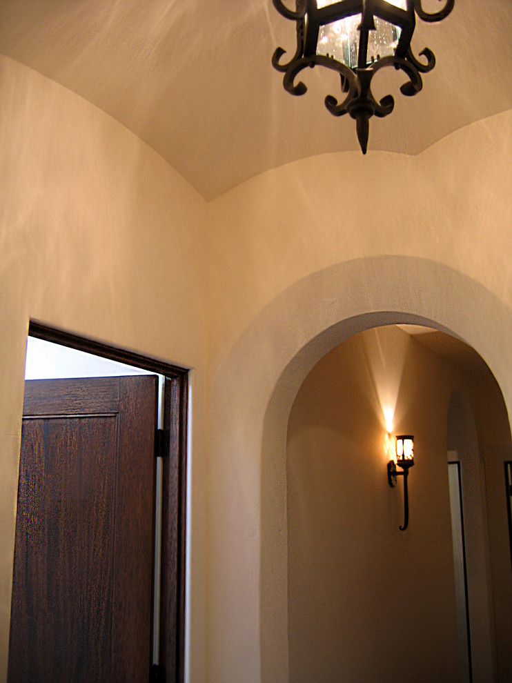 Photo of a mid-sized mediterranean hallway in Santa Barbara with white walls, terra-cotta floors and red floor.