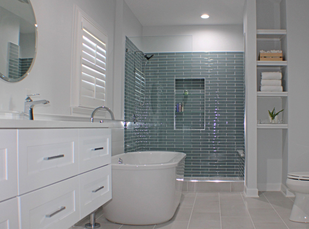 This is an example of a large contemporary master bathroom in Nashville with shaker cabinets, white cabinets, a freestanding tub, an alcove shower, green tile, glass tile, white walls, porcelain floors, an undermount sink, engineered quartz benchtops, grey floor, an open shower, white benchtops, a niche, a double vanity, a freestanding vanity and planked wall panelling.