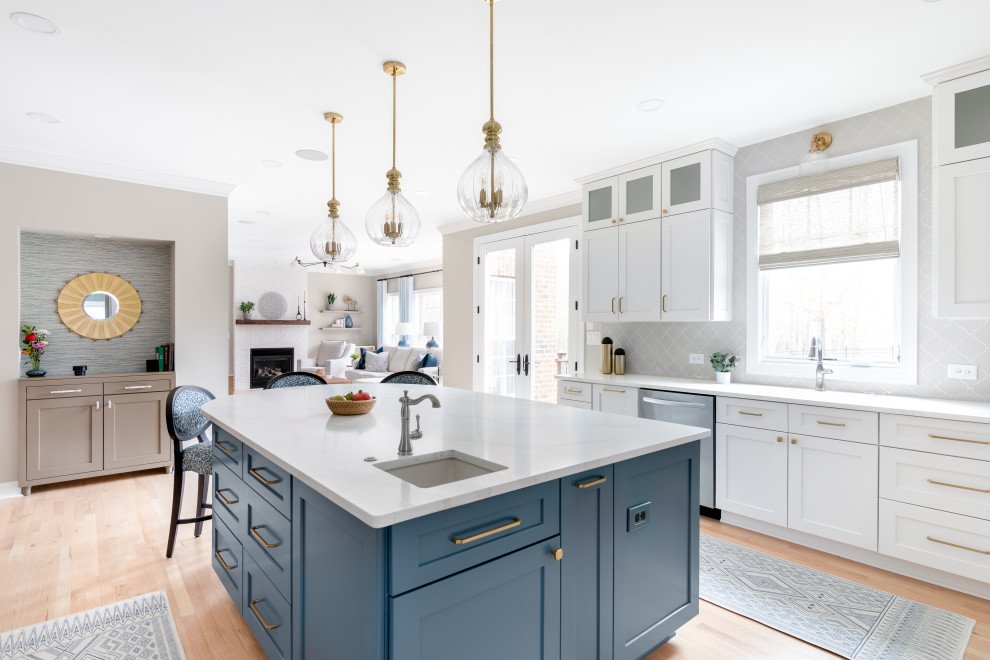 Inspiration for a large transitional light wood floor and brown floor eat-in kitchen remodel with a drop-in sink, shaker cabinets, quartz countertops, gray backsplash and an island
