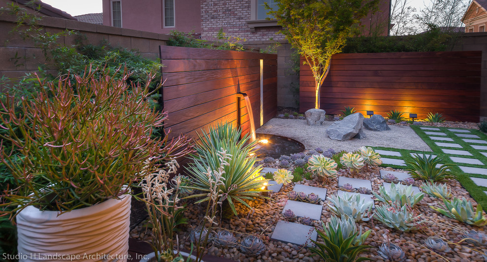Inspiration for a mid-sized contemporary partial sun xeriscape in Orange County with a water feature and gravel.