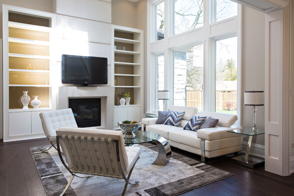 This is an example of a large transitional open concept family room in Toronto with beige walls, dark hardwood floors, a standard fireplace, a concrete fireplace surround, brown floor and a wall-mounted tv.