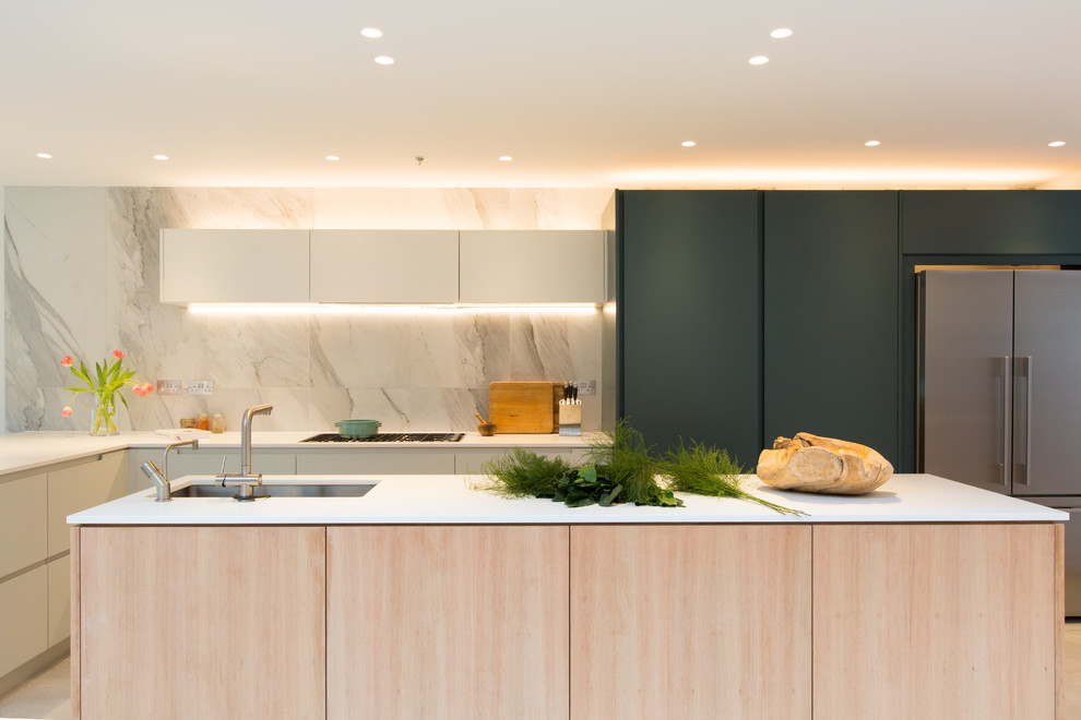 Expansive scandinavian galley open plan kitchen in London with an integrated sink, flat-panel cabinets, light wood cabinets, solid surface benchtops, white splashback, marble splashback, stainless steel appliances, concrete floors, with island, grey floor and white benchtop.