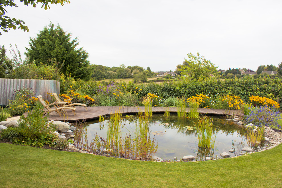 This is an example of a mid-sized country backyard full sun garden for summer in Other with a water feature and decking.
