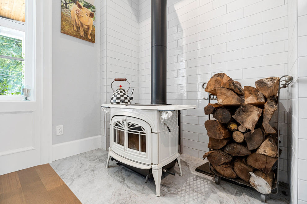 Cette image montre une petite salle à manger traditionnelle avec une banquette d'angle, un mur gris, un sol en bois brun, un poêle à bois, un manteau de cheminée en carrelage et un sol marron.