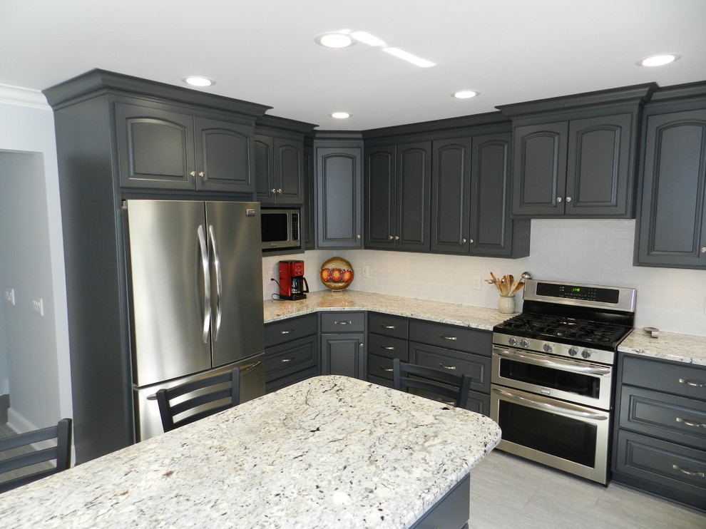 Inspiration for a mid-sized transitional l-shaped porcelain tile and beige floor enclosed kitchen remodel in Cleveland with raised-panel cabinets, gray cabinets, granite countertops, white backsplash, subway tile backsplash, stainless steel appliances, an island and an undermount sink