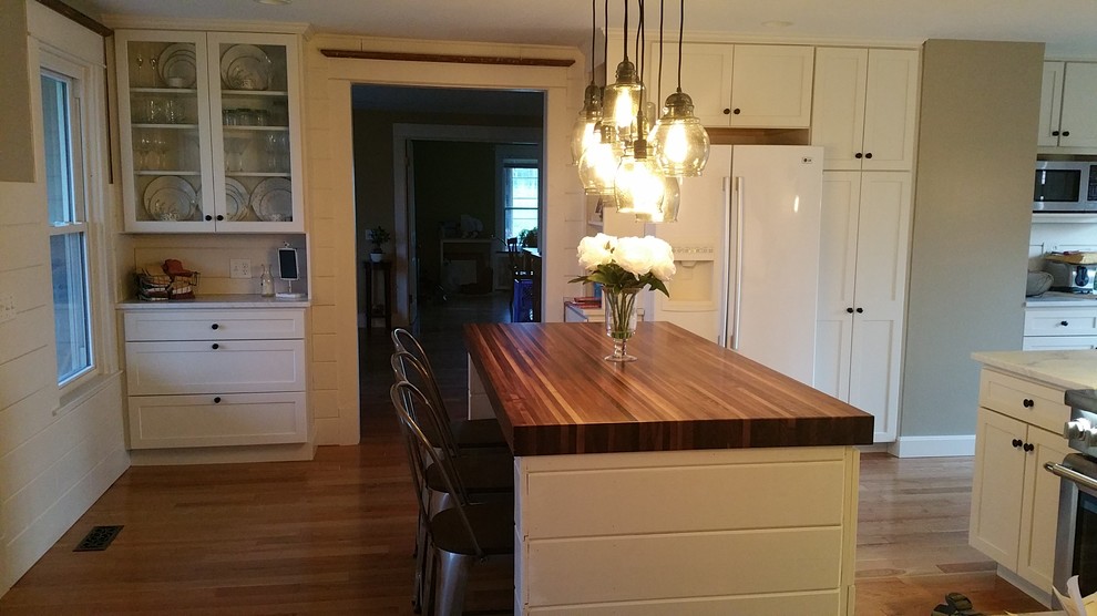 Inspiration for a large light wood floor eat-in kitchen remodel with recessed-panel cabinets, white cabinets, white backsplash, white appliances, an island and wood countertops