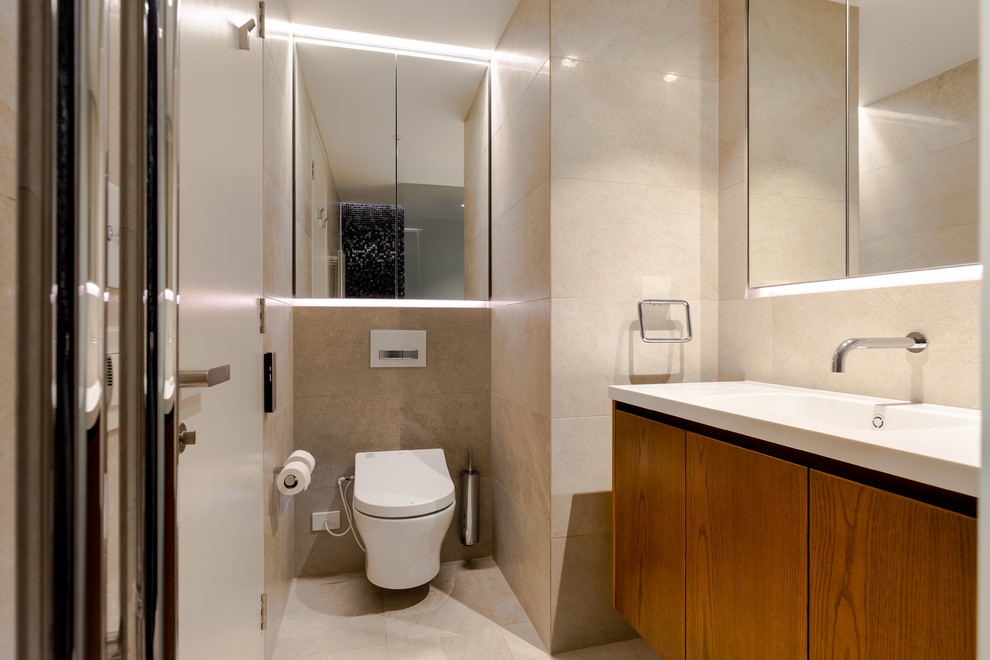 This is an example of a contemporary 3/4 bathroom in Sydney with flat-panel cabinets, medium wood cabinets, a wall-mount toilet, beige tile, beige walls, an integrated sink, beige floor and white benchtops.