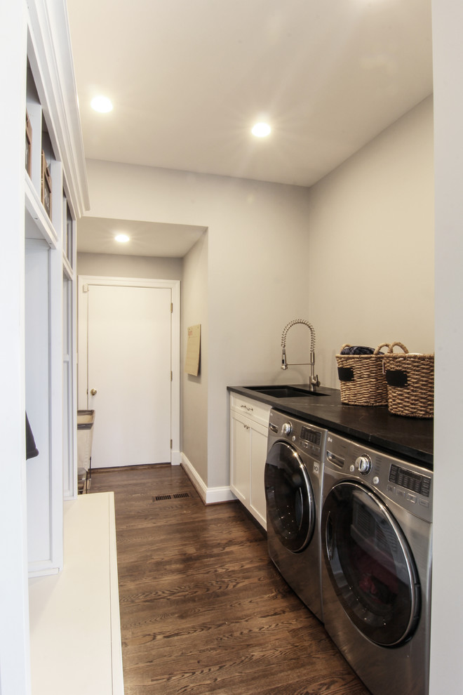 Design ideas for a mid-sized transitional galley utility room in DC Metro with an undermount sink, recessed-panel cabinets, white cabinets, soapstone benchtops, grey walls, dark hardwood floors and a side-by-side washer and dryer.