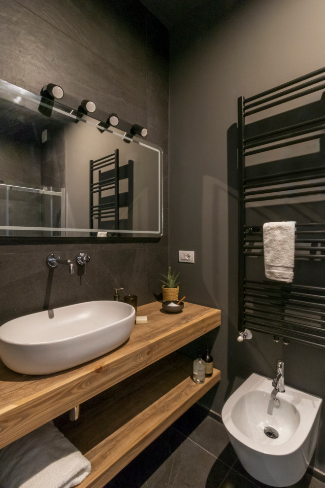 Inspiration for a mid-sized contemporary 3/4 bathroom in Milan with open cabinets, light wood cabinets, a wall-mount toilet, gray tile, grey walls, porcelain floors, a vessel sink, wood benchtops, grey floor and beige benchtops.