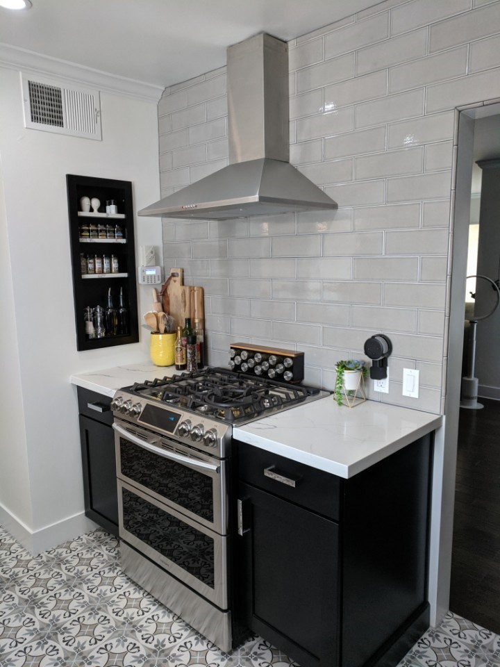This is an example of a mid-sized traditional galley separate kitchen in Phoenix with a farmhouse sink, flat-panel cabinets, black cabinets, quartzite benchtops, grey splashback, subway tile splashback, stainless steel appliances, ceramic floors, no island, grey floor and white benchtop.