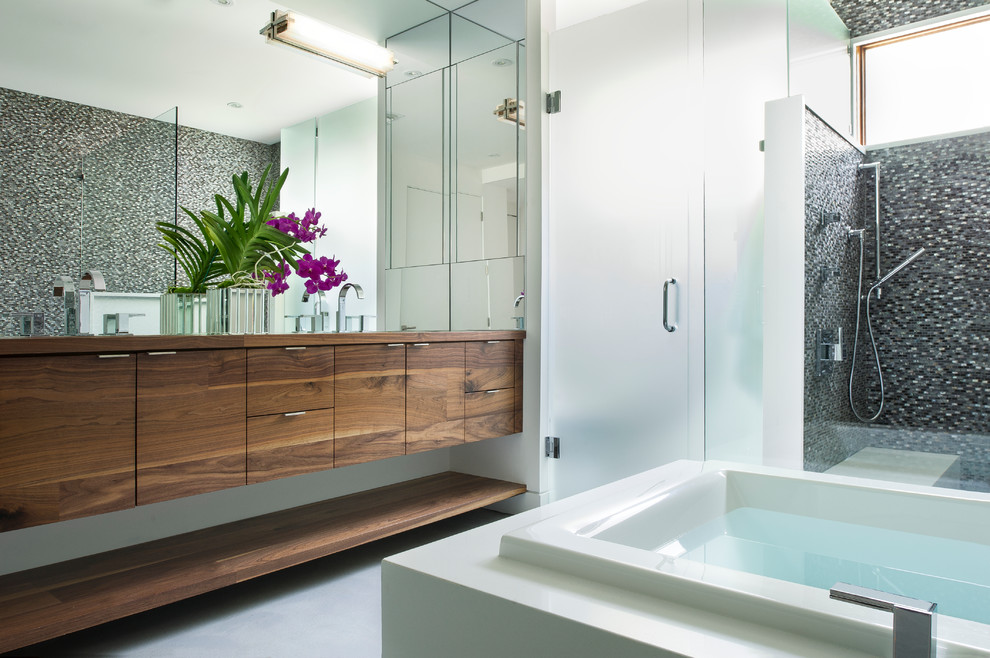 Inspiration for a large contemporary master bathroom in Orlando with flat-panel cabinets, medium wood cabinets, a drop-in tub, an open shower, a wall-mount toilet, white tile, mosaic tile, white walls, concrete floors, wood benchtops and an undermount sink.