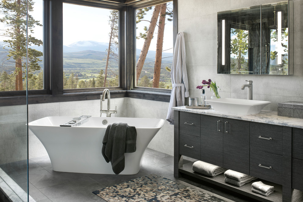 Design ideas for a country master bathroom in Denver with black cabinets, a freestanding tub, gray tile, grey walls, a vessel sink, marble benchtops, grey floor, multi-coloured benchtops and flat-panel cabinets.