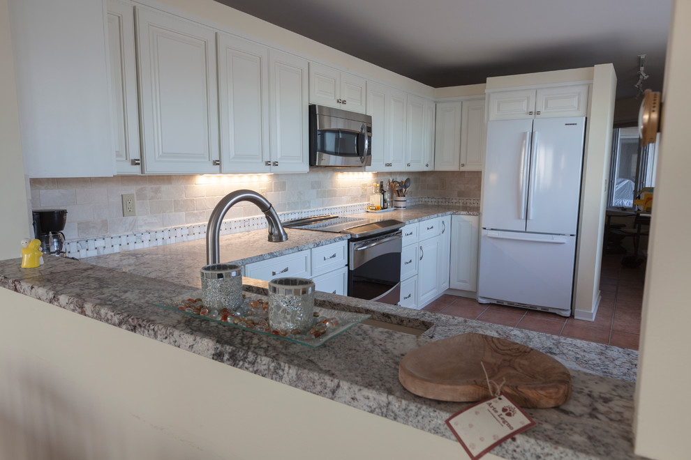 This is an example of a mid-sized transitional u-shaped separate kitchen in Bridgeport with an undermount sink, raised-panel cabinets, white cabinets, granite benchtops, beige splashback, stone tile splashback, stainless steel appliances and no island.